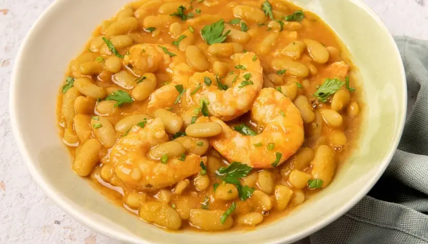 Plato de verdinas con langostinos, guisadas en una salsa sabrosa y adornadas con perejil fresco.