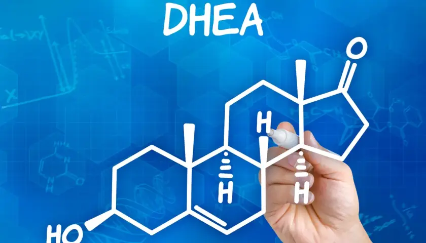 DHEA co to? Rysunek przedstawia wzór chemiczny DHEA, hormonu steroidowego, z ręką piszącą markerem.