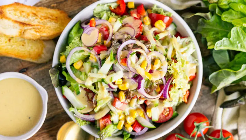 Frischer Salat mit Tomaten, Gurken, Zwiebeln und Mais, beträufelt mit einem köstlichen Salatdressing. Ein tolles Salatdressing Rezept!