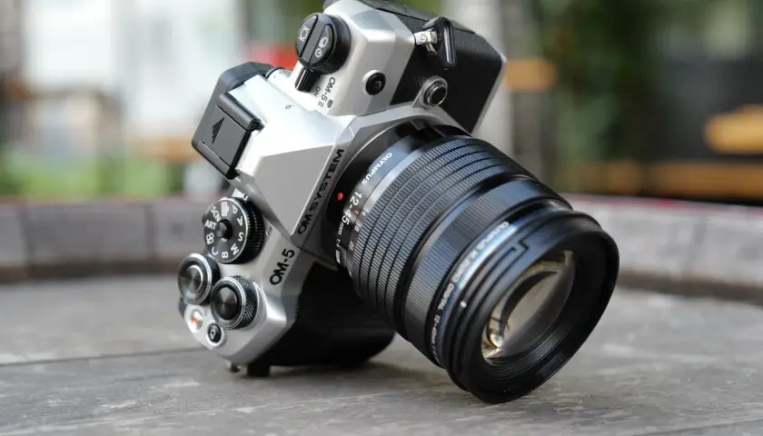 Srebrny aparat OM SYSTEM OM-5 z obiektywem M.ZUIKO DIGITAL 12-45mm 1:4, gotowy do uchwycenia każdej chwili.