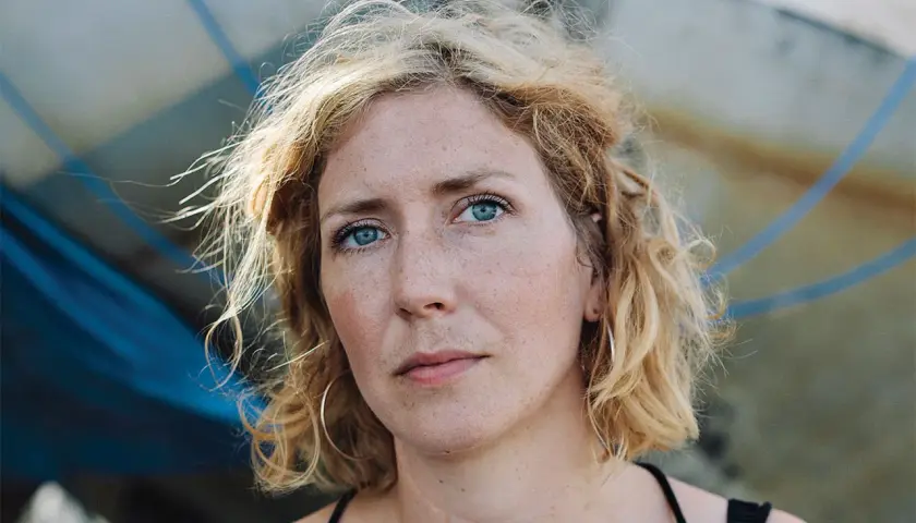Amanda Svensson med blå ögon och blont, ostyrigt hår. Hon bär stora örhängen och tittar rakt in i kameran.