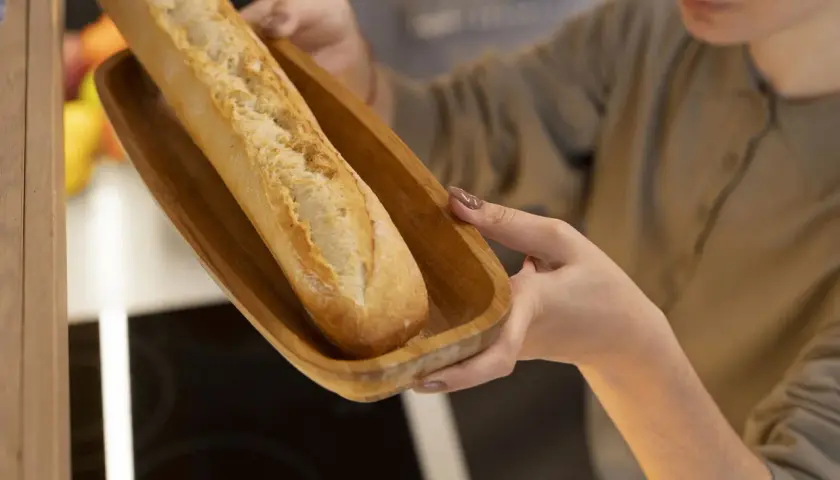 Frau hält Holzschale mit Baguette zum Auftauen.