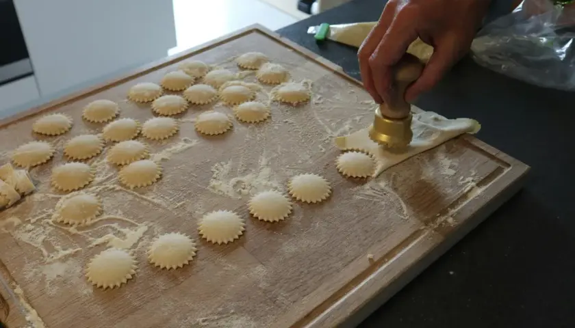 Ręcznie robione ravioli z pysznym farszem do ravioli, przygotowywane na drewnianej desce.