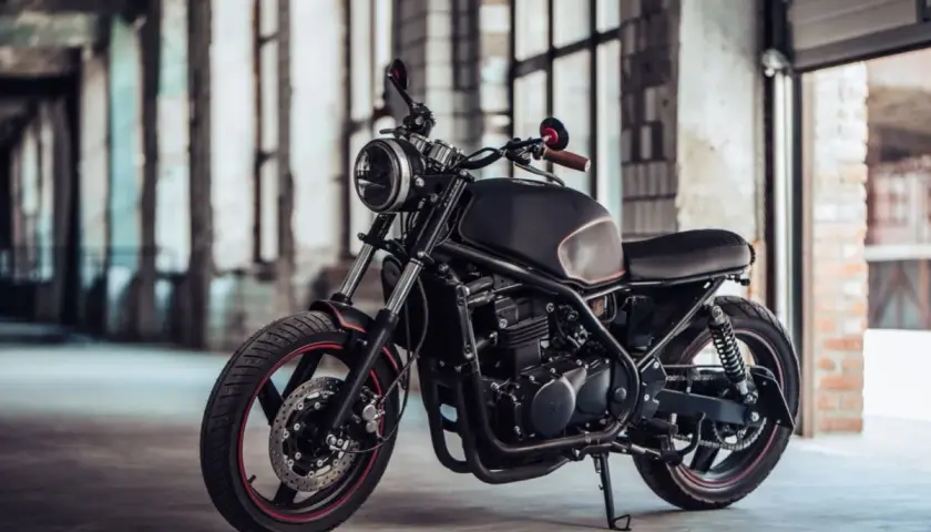 Elegante moto customizada, negra y con detalles rojos, lista para la aventura. Una moto sin papeles que inspira libertad y rebeldía.