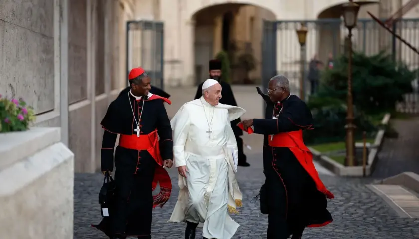 Papst Franziskus geht mit zwei Kardinälen. Was macht der Papst den ganzen Tag? Er spricht, betet und kümmert sich um die Menschen.