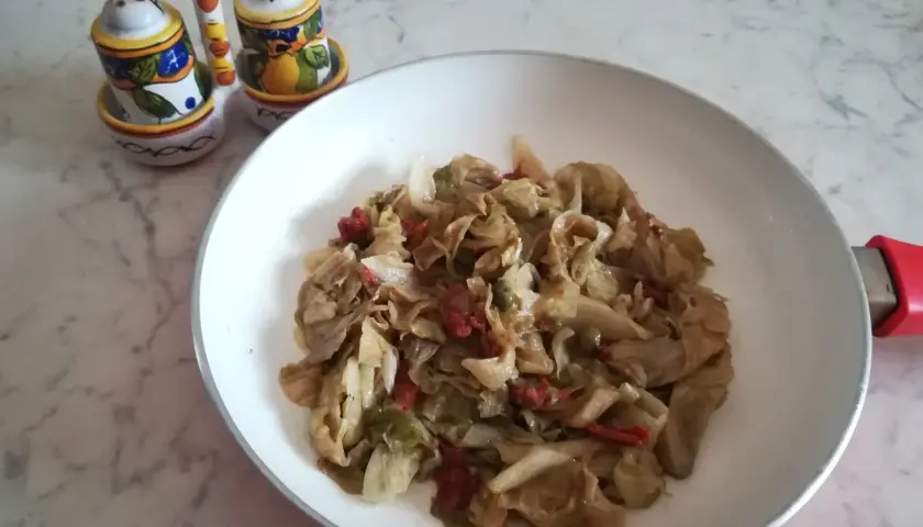Insalata iceberg cotta in padella con pomodori secchi. Un piatto semplice e gustoso.