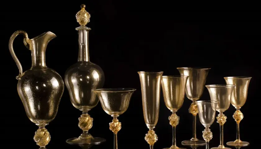 Service en verre doré, digne d'un musée du verre à Venise, avec carafe et verres aux pieds sculptés.