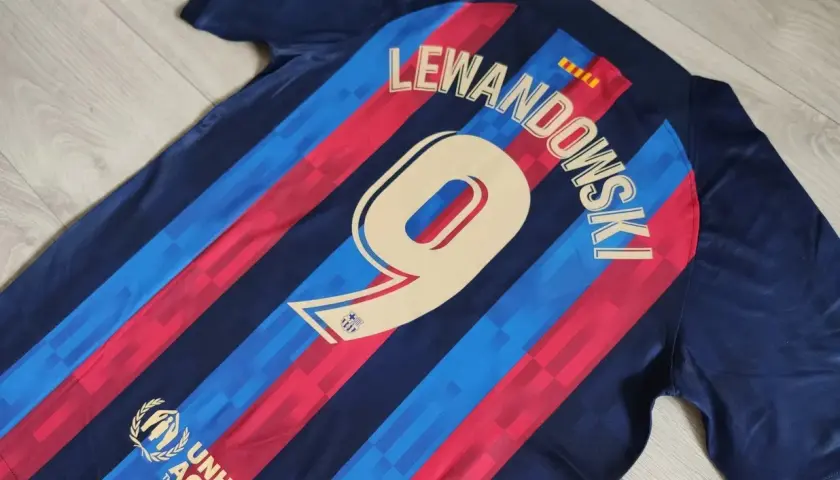Koszulki meczowe FC Barcelona z nazwiskiem Lewandowskiego i numerem 9. Widoczny też herb UNHCR.