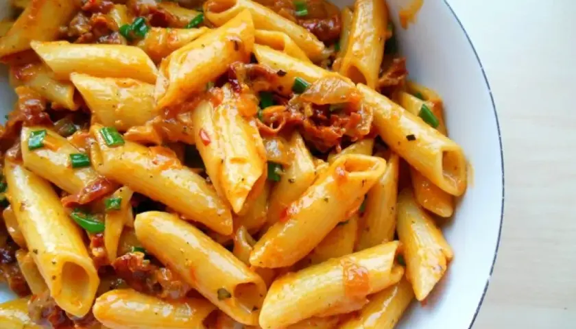 Penne z sosem z suszonych pomidorów i zieloną cebulką, apetyczne danie pełne smaku.