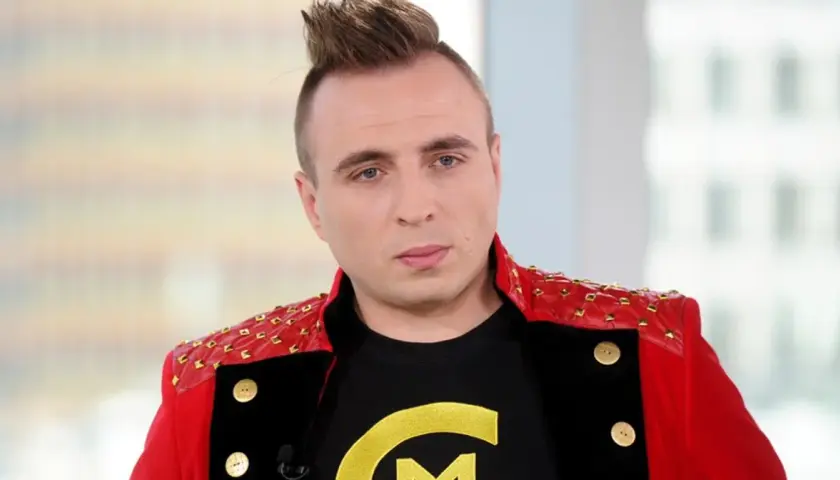 Czadomen w czerwonej marynarce z ćwiekami i czarnej koszulce z żółtym logo.