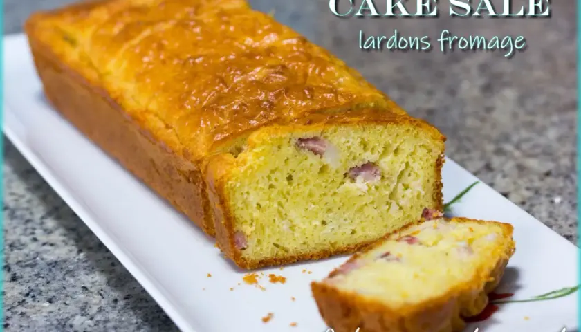 Un cake salé aux lardons et fromage, doré et moelleux, avec une tranche coupée pour révéler les morceaux savoureux.
