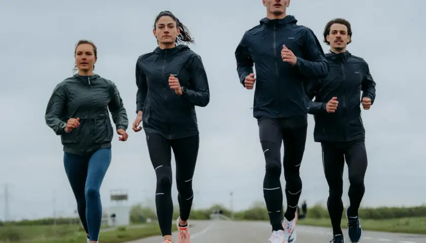 Cztery osoby biegną po drodze, ubrani w sportowe kurtki i legginsy. Wyglądają, jakby właśnie odkryli, kiedy wynaleziono bieganie.