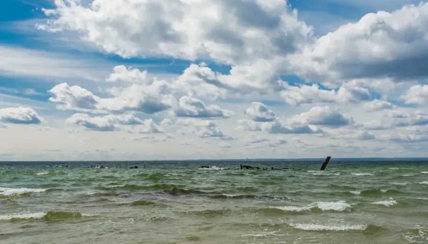 Falujące morze bałtyckie, które jest częścią oceanu atlantyckiego, pod błękitnym niebem z kłębiastymi chmurami.