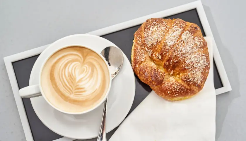 Cappuccino con latte art e brioche americane cosparse di zucchero.