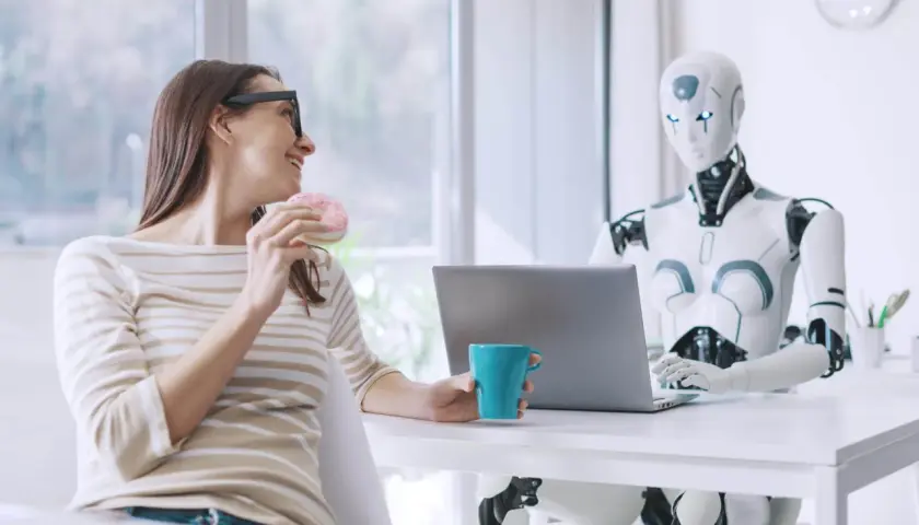 Kobieta z pączkiem i kubkiem kawy rozmawia z robotem przy laptopie. Oryginalna scena z przyszłości.