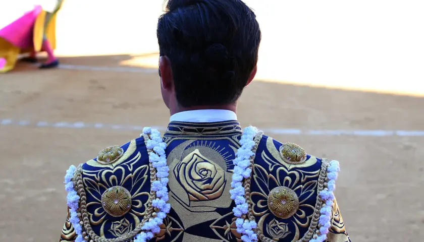 Detalle de la espalda de un torero con bordados dorados y azules, mostrando los vibrantes colores taurinos.