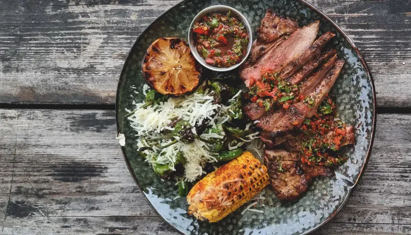 En tallrik med saftigt grillat secreto iberico, serverat med grillad majskolv, citron och en fräsch salsa. Ett perfekt secreto iberico recept för en festmåltid.