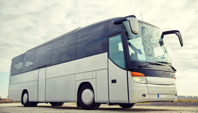 Biały autokar turystyczny na tle nieba z chmurami.