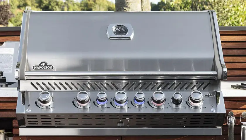 Barbecue à gaz Napoleon avec couvercle fermé, prêt pour de nouvelles recettes. Ses boutons lumineux indiquent la température parfaite.