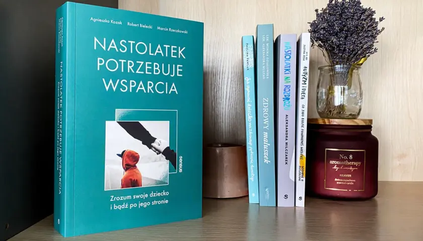 Książka "Nastolatek potrzebuje wsparcia" na półce z innymi książkami i świecą.