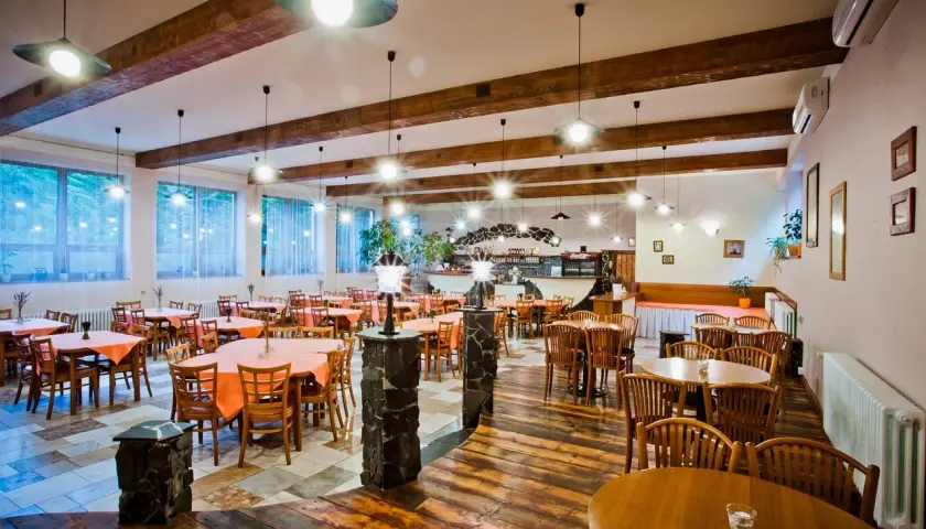 Szukasz miejsca, gdzie zjeść w Mielnie? Przytulna restauracja z drewnianymi belkami i stołami nakrytymi pomarańczowymi obrusami zaprasza.