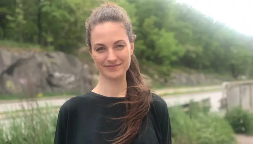 Petra Wahlgren ler mot kameran utomhus, med en grönskande bakgrund.