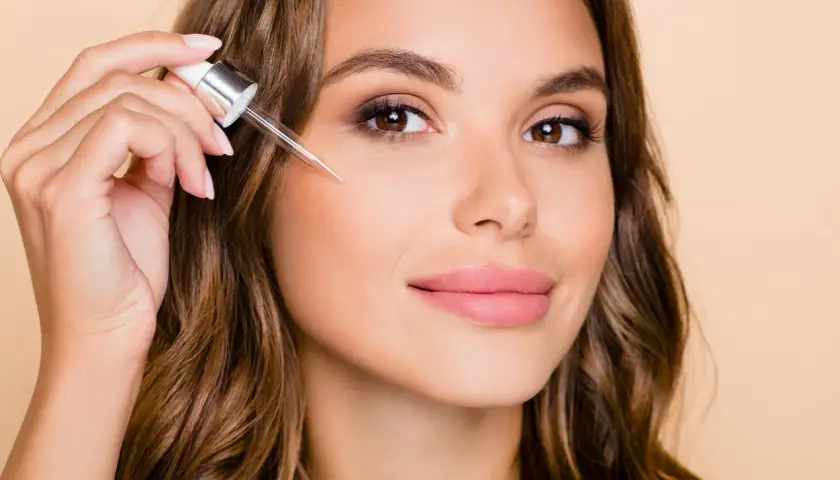 Kobieta aplikuje serum z pipetką, rozpoczynając swoją kurację retinolem dla promiennej cery.
