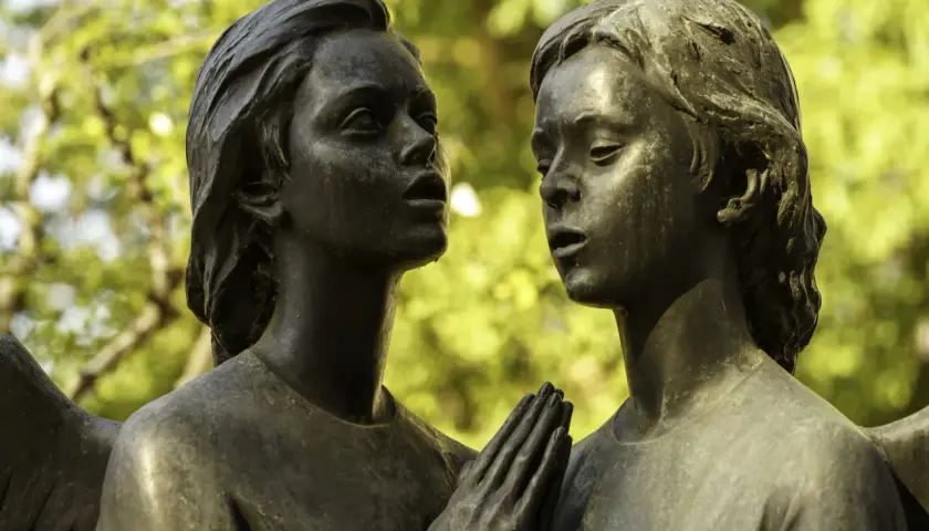 Deux visages d'anges en bronze se font face. Leurs mains jointes aident à comment reconnaître du bronze, patiné par le temps.
