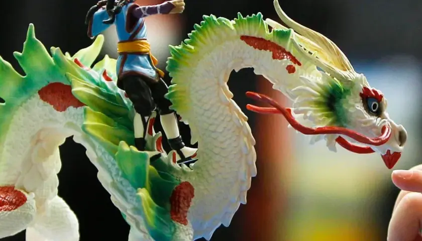 Ein Junge reitet auf einem weißen Drachen mit grünen und roten Akzenten. Ein detailreiches Schleich Spielzeug, das Fantasie und Abenteuer weckt.