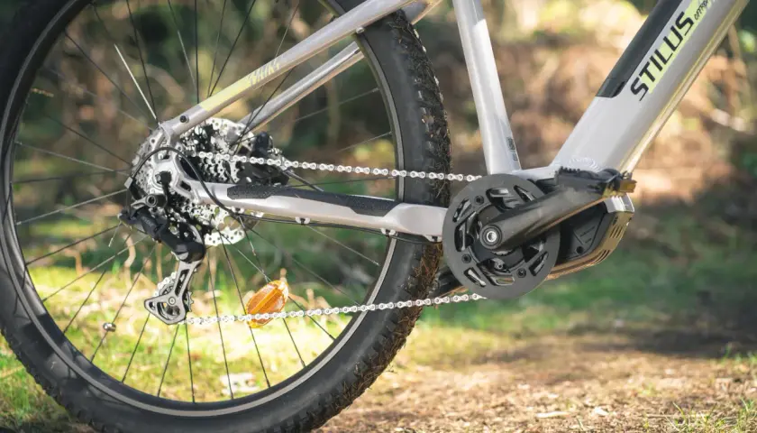 Zbliżenie na tylne koło roweru elektrycznego i mechanizm korbowy. Widać zębatkę, łańcuch i przerzutkę. Długość korby jest kluczowa dla komfortu jazdy.
