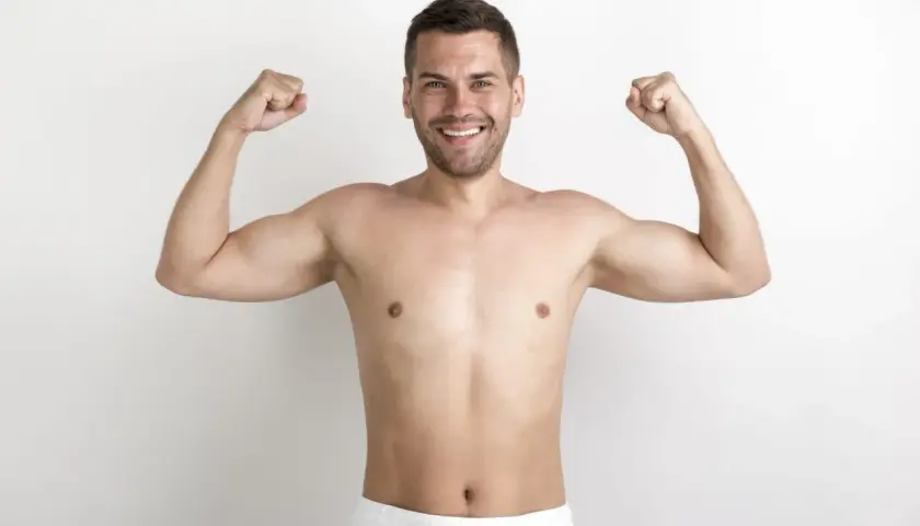 Uśmiechnięty mężczyzna prezentuje swoją szewską klatkę piersiową, napinając bicepsy.
