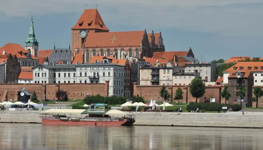 Widok na średniowieczny zespół miejski Torunia z Wisły. Widać katedrę, mury obronne i kamienice.