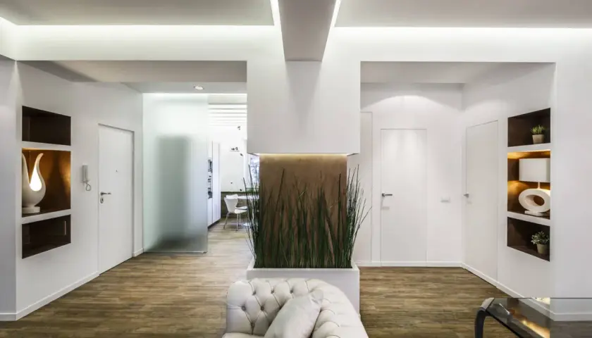 Interni moderni con pilastri in cartongesso che creano nicchie decorative e un'elegante parete divisoria con piante.