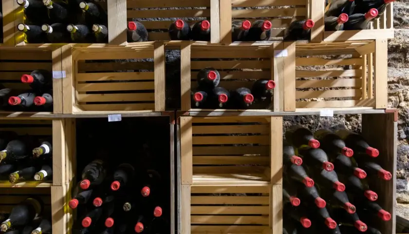Weinlager mit vielen Flaschen in Holzkisten. Manche Flaschen haben rote Kappen. Die Frage, ob Wein ein Ablaufdatum hat, bleibt offen.