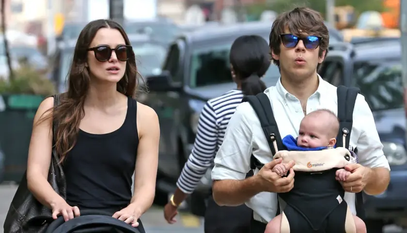 Keira Knightley z mężem i ich maleńkim dzieckiem w nosidełku, spacerując po ulicy.