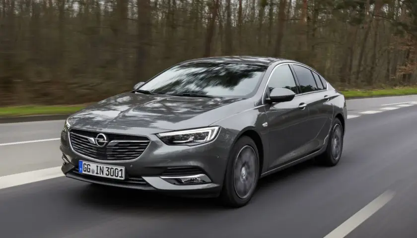 Grå Opel Insignia kör på en väg genom en skog. Kanske ett opel insignia problem med att hitta rätt väg?