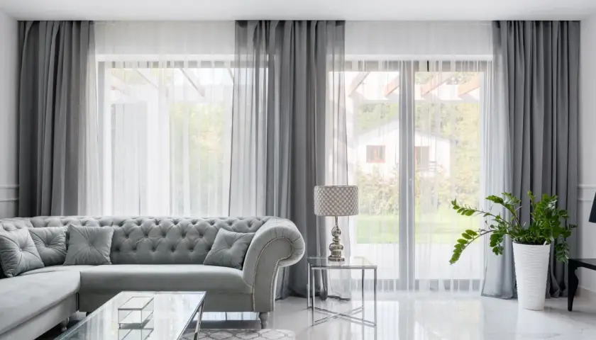 Elegancki salon z szarymi zasłonami do sufitu, które pięknie otulają okna, tworząc przytulną atmosferę.