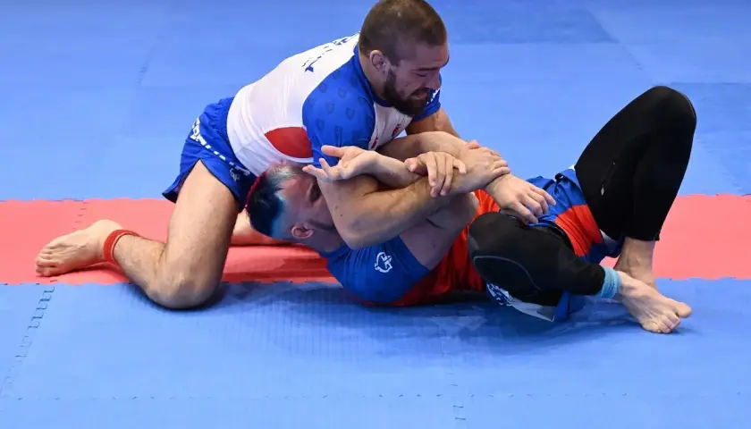 Dwóch mężczyzn walczy na macie. Jeden klęczy, drugi leży. To właśnie bjj co to za sport?