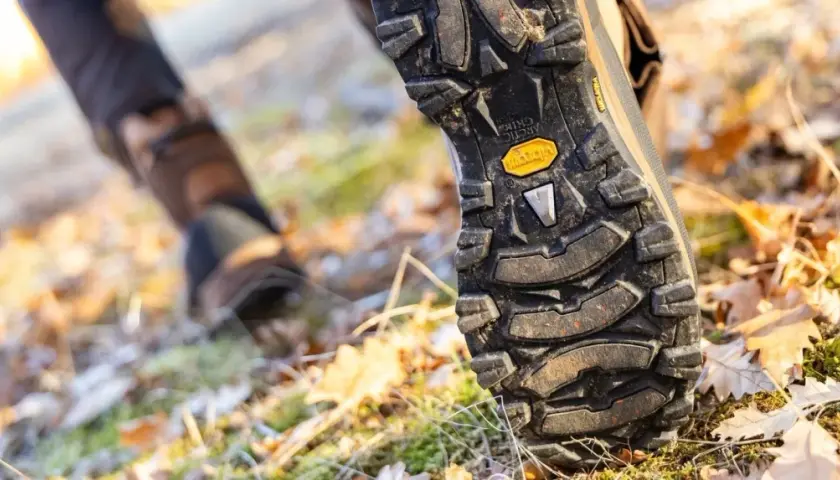 Close-up of a hiking boot sole on a forest floor. Learn how to break in hiking boots for comfortable adventures.