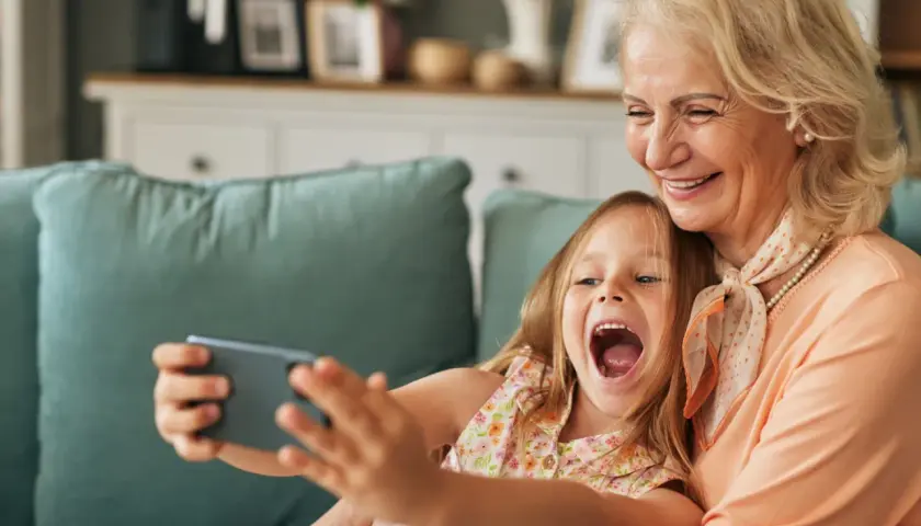 Großmutter und enkel kinder machen ein Selfie. Sie lachen beide vor Freude.