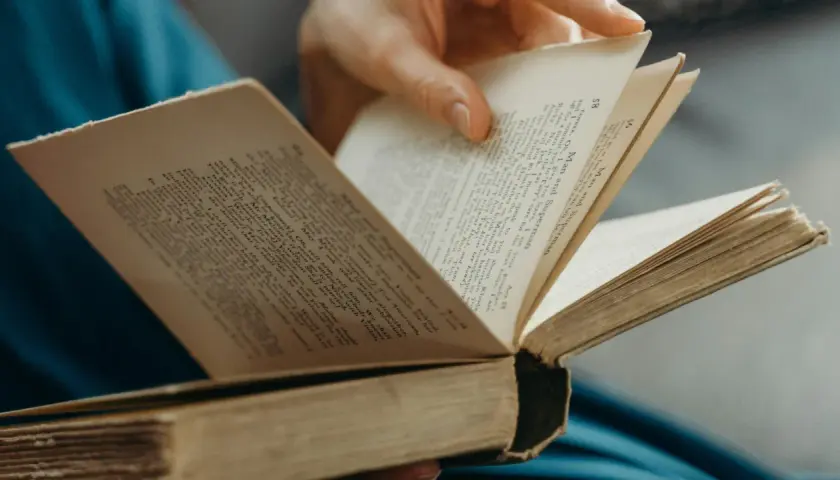 Eine Hand blättert in einem alten Buch. Der Titel "Man and Superman" ist sichtbar. Ein guter historischer Roman zum Eintauchen.