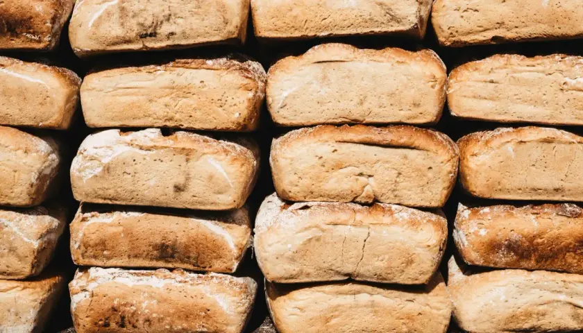 Stos chleba, który zastanawia, czy pies może jeść chleb. Każdy bochenek ma złocistą skórkę i lekko posypany mąką.
