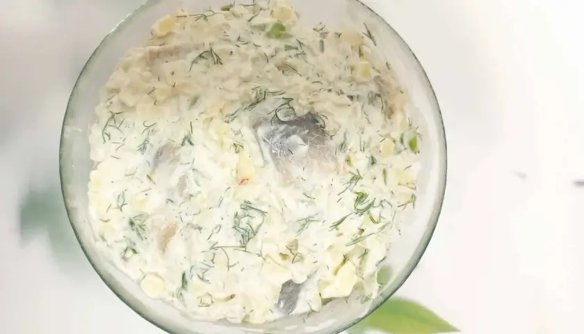 Pyszny przepis na śledzie w śmietanie z jabłkiem i ogórkiem, posypane świeżym koperkiem. Idealna przekąska!