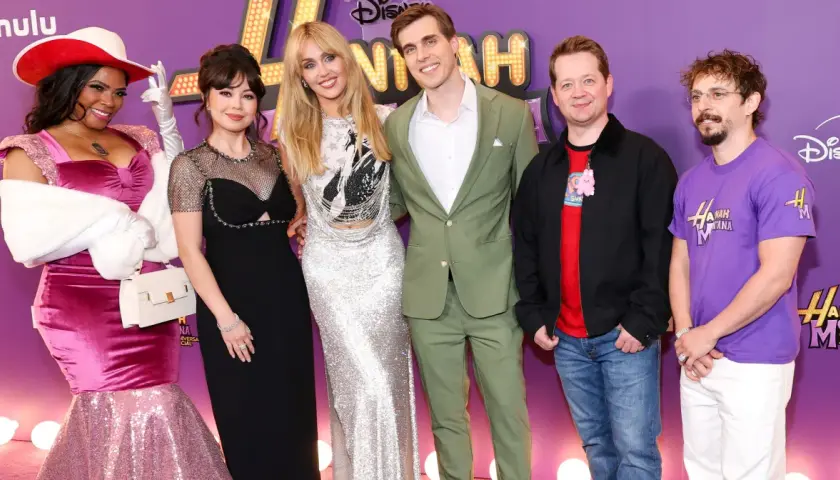Hannah Montana obsada świętuje 20. rocznicę serialu. Gwiazdy w olśniewających strojach pozują na fioletowym dywanie.