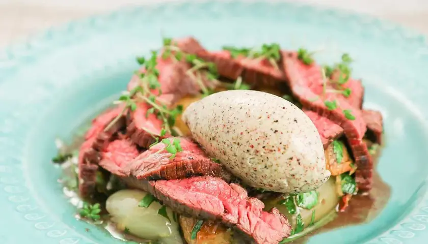 Skivad flankstek Morberg med potatis och en klick potatispuré, garnerad med örter.