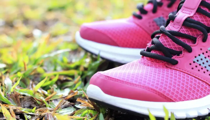 Rosa Laufschuhe mit schwarzen Schnürsenkeln auf Gras. Die richtige Wahl für welche Schuhe bei Kniearthrose?
