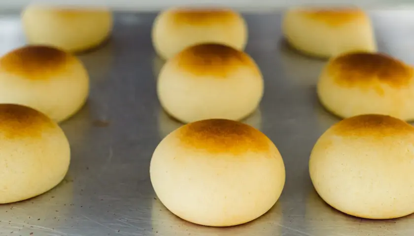 Pan de bono recién horneados, dorados y esponjosos, listos para disfrutar.