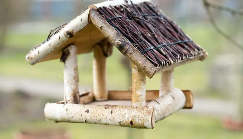 Ein selbstgebautes vogelfutterhaus aus Holz und Zweigen, bereit für gefiederte Gäste.