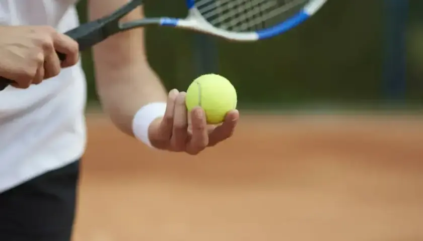 Gracz trzyma piłkę tenisową, gotowy do serwisu. Kluczowy moment w tie breaku.