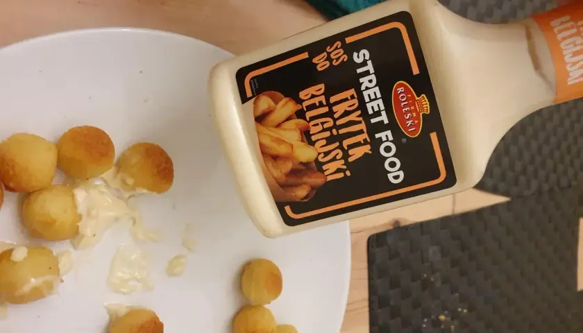 Kula frytek na talerzu, obok butelka sosu belgijskiego Street Food.
